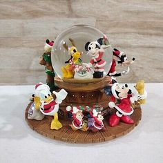 mickey mouse figurines are on display in a snow globe with santa claus and other disney characters