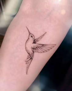 a small hummingbird tattoo on the arm