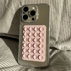 a cell phone case that has some circles on the back and inside of it, sitting on top of a bed