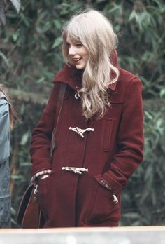 a woman in a red coat is talking on her cell phone