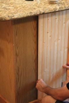 a man is sitting on the floor with his feet propped up in front of an unfinished cabinet