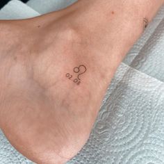 a small tattoo on the foot of a woman's left foot, with circles and hearts