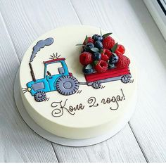 a cake with berries and raspberries on the top is decorated like a tractor