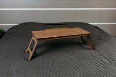 a small wooden table sitting on top of a bed next to a potted plant