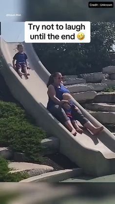 two children are sliding down a slide at the park, and one child is sitting on it