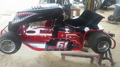 a red and black race car sitting on top of a metal stand in a garage