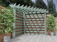 a large wooden gate in the middle of a brick wall with potted plants on either side