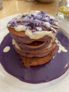 a stack of cookies covered in purple icing on top of a white and blue plate