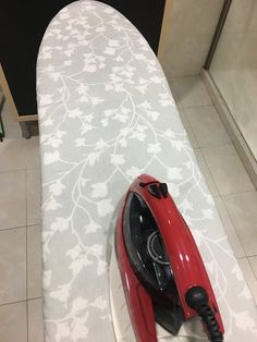 a red ironing board sitting on top of a tiled floor next to a wall