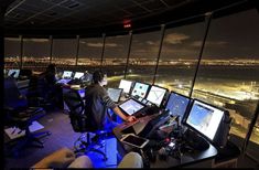 a man sitting at a desk in front of multiple computer monitors on top of a building