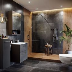 a bathroom with a toilet, sink and shower stall in the corner next to a potted plant