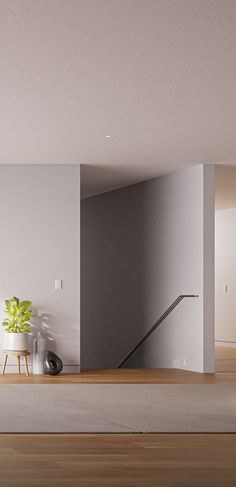 an empty room with a plant in the corner and stairs leading up to the second floor