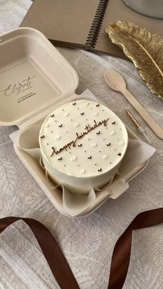 a cake sitting on top of a white plate next to a brown ribbon and fork