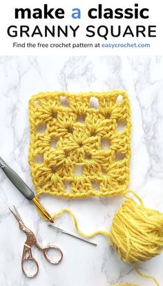 the crochet granny square is next to scissors and yarn on a marble surface