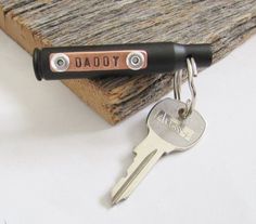 a couple of keys that are on top of a keychain with the word dad written on it