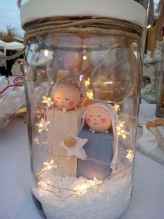 there is a glass jar with some lights in it and two dolls inside the jar