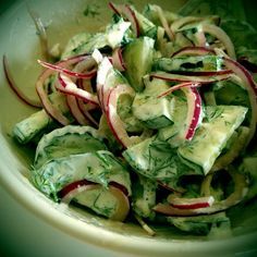 a white bowl filled with cucumber and radishes