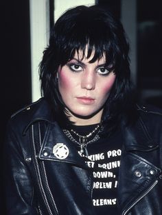 a woman with black hair and piercings wearing a leather jacket is looking at the camera