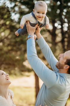 a man holding a baby up in the air