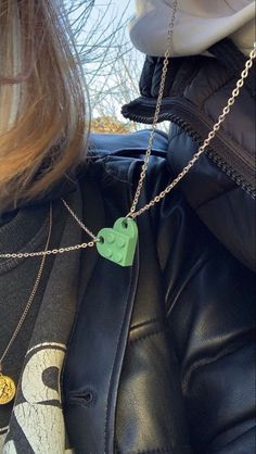 a woman wearing a black leather jacket with a green elephant pendant on it's neck