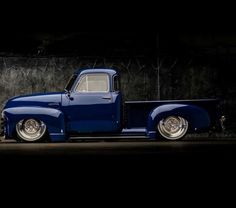 an old blue truck is parked in the dark