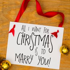 a white sign with red ribbon hanging from it's side on top of a wooden table