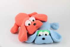 two crocheted stuffed animals laying next to each other on a white table top