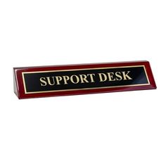 a red and black sign that says support desk with gold lettering on the bottom, in front of a white background