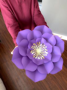 a person holding a large purple paper flower