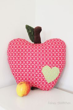 a stuffed apple sitting on top of a white shelf