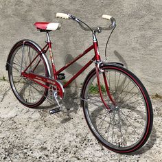 a red bicycle is parked against a concrete wall