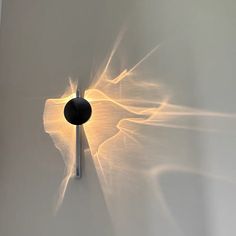 a white wall with a light shining on it and a round object in the middle