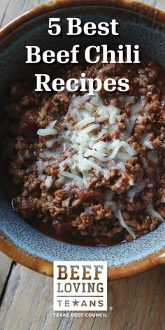 a bowl filled with chili and cheese on top of a wooden table