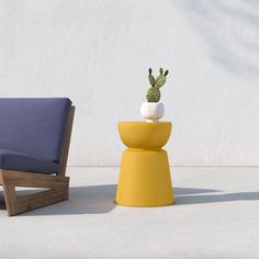 a yellow stool with a cactus sitting on top of it next to a blue chair