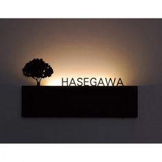 a sign that reads hasegawa with a tree in the middle and light behind it