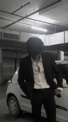 a man standing next to a white car in a parking garage