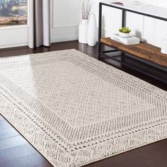 a large white rug on top of a hard wood floor next to a wooden table