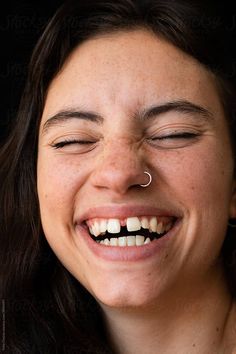 a woman smiling with her eyes closed and nose piercing in front of her face by jodi jones for stockstation photography