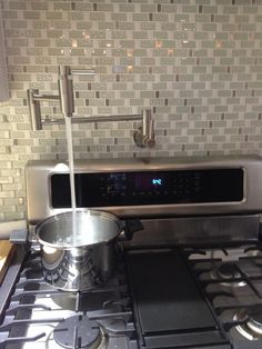 a stainless steel stove top oven sitting next to a pot on the burner in a kitchen