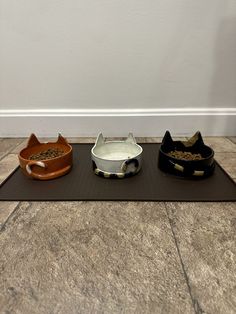 three cat bowls sitting on top of a mat