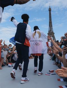 two people are walking down the street with their hands in the air and one person is holding an olympic flag