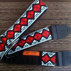 two red, white and blue patterned straps on a brown surface with an orange tag