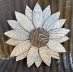 a wooden sunflower is mounted to the side of a metal wall