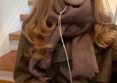 a woman with long blonde hair is listening to music on her headphones while wearing a scarf