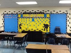 an empty classroom with desks and chairs in front of the bulletin board that has pictures on it