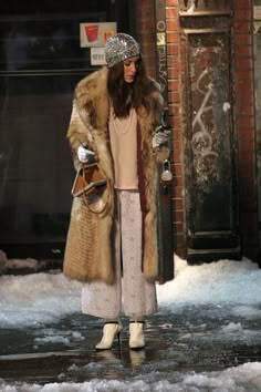 a woman is standing in the snow with her hand on her hip and wearing a fur coat