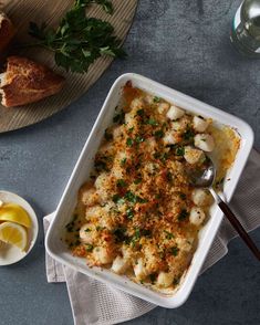 a casserole dish with bread and lemons on the side next to it