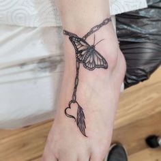 a woman's foot with a butterfly and heart tattoo on the left side of her ankle