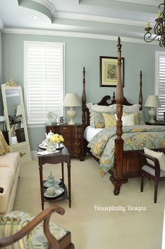 a bed room with a neatly made bed next to a chair and two tables in front of it