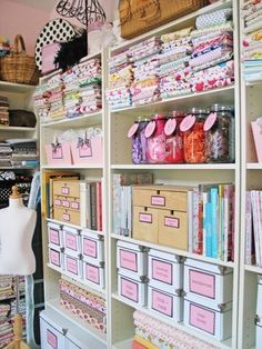 an organized closet with lots of crafting supplies on shelving units and pink boxes